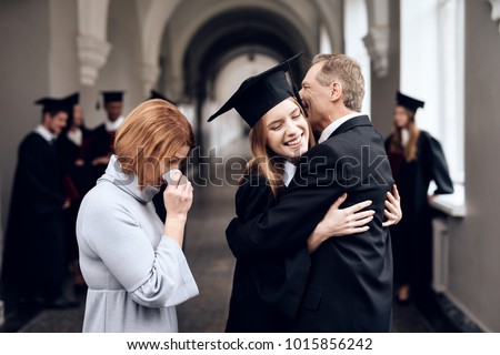 Parents congratulate the student, who finish their studies at the university. He graduates. They are very happy about this.