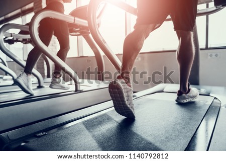 Close up. Man and Young Woman on Treadmills in Gym. Man with Athletic Body. Healthy Lifestyle and Sport Concepts. Young Woman in Training Club. Active Indoor Training. Sport Equipment.