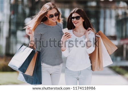 Young Women with Shopping Bags Walking City Street. Sale, Consumerism and People Concept. Shopping and Tourism Concept. Girls Bags Walking Down the Street on Sunny Day after Good Shopping.