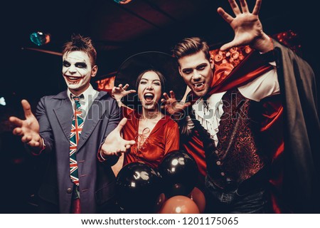 Young People in Costumes Celebrating Halloween. Group of Young Happy Friends Wearing Halloween Costumes having Fun at Party in Nightclub by doing Scary faces. Celebration of Halloween