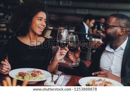African American Couple Dating in Restaurant. Romantic Couple in Love Dating. Cheerful Man and Woman with Menu in a Restaurant Making Order. Romantic Concept. Cheers Classes Red Wine.