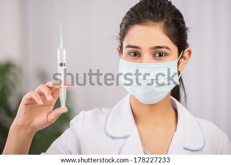 Indian doctor wearing a white coat with syringe