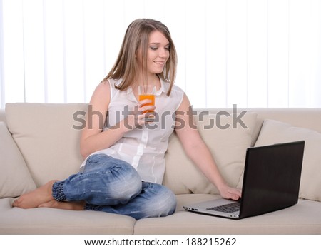 Work at home. Young beautiful woman working with a laptop sitting on sofa at home