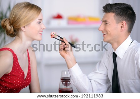 Couple eating sushi. Beautiful young couple sitting together at the restaurant and eat sushi