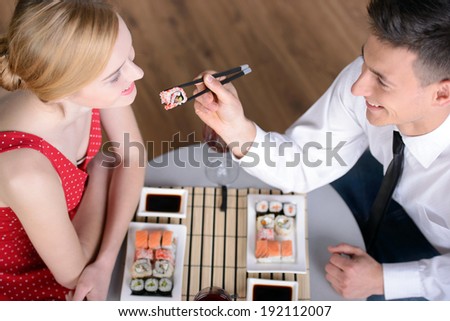 Couple eating sushi. Beautiful young couple sitting together at the restaurant and eat sushi