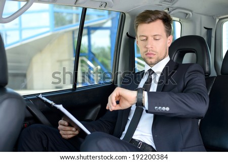 Young successful businessman riding in the car