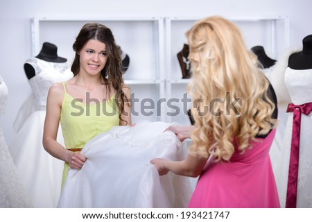 Two girlfriends - bridesmaids- having fun - looking for dresses for wedding