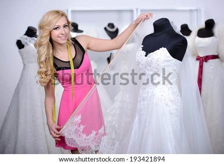 Designer wedding dresses, measures the dress on a mannequin in her shop
