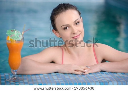 Spa & Wellness. Closeup of pretty smiling woman with juice by the pool