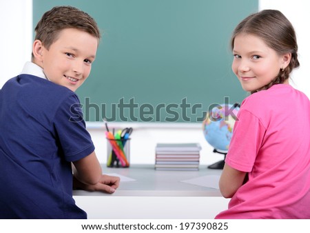 Studying together. Rear view of two little classmates reading a book together