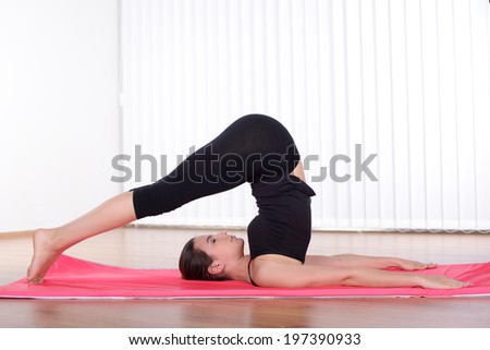 Woman working out. Side view of attractive young woman training on yoga mat