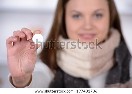 Woman taking aspirin. Young woman holding pill upon glass with water and expressing negativity while sitting in bed at her apartment