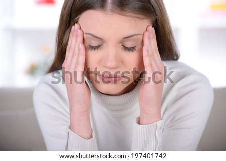 Feeling awful headache. Frustrated young woman holding head in hands and expressing negativity while sitting in bed at her apartment