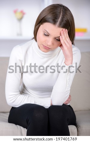 Feeling awful headache. Frustrated young woman holding head in hands and expressing negativity while sitting in bed at her apartment