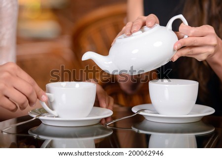 Two friends drinking tea and talking in the cafe