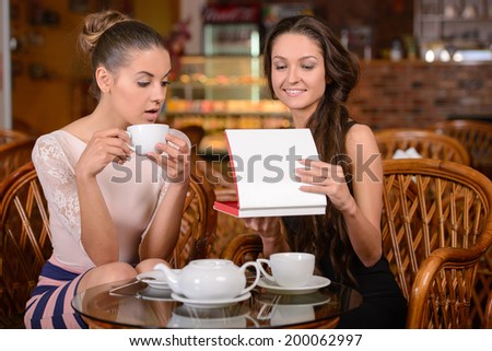 Two friends drinking tea and talking in the cafe