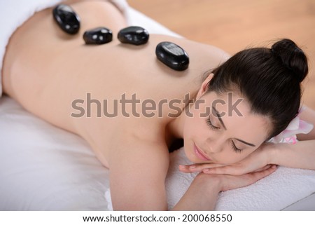 Beautiful relaxing woman with stones on her back in a Spa