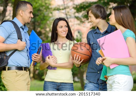 Group portrait of four smiling cheerful students outdoors in park