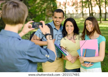 Group of happy young college students do photography at mobile phone in the park