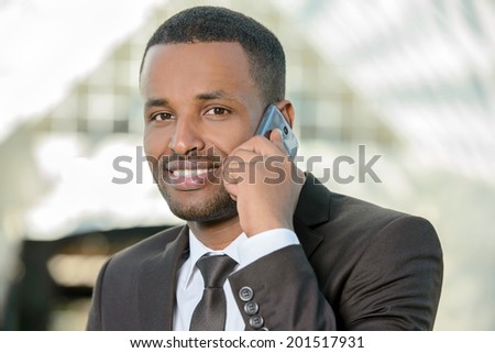 Businessman on the phone. Cheerful young African man in formalwear talking on the mobile phone and smiling