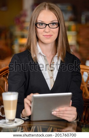 Businesswoman with digital tablet. Beautiful young woman in formalwear working on digital tablet while sitting at the restaurant