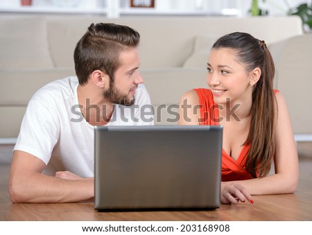 Young people lying on the floor at home and using laptop at home