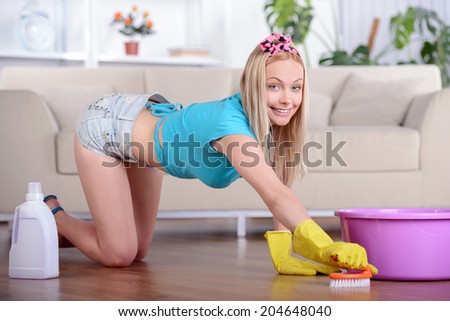 Beautiful housewife cleans the floor at home