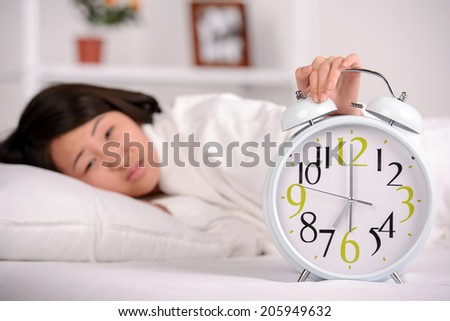 Sleep. Portrait of Asian woman sleeping on the bed at home. Great alarm clock in the foreground