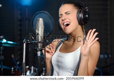 Portrait of young woman recording a song in a professional studio
