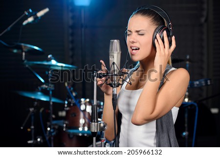 Portrait of young woman recording a song in a professional studio