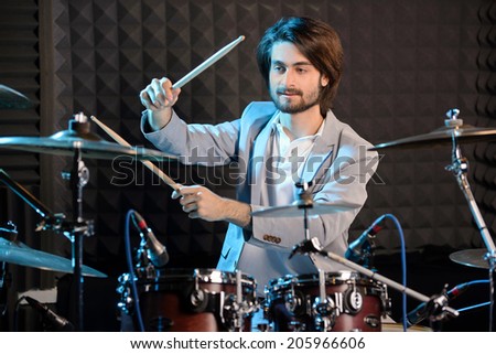 Young man behind drum-type installation in a professional recording studio