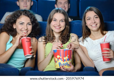 Exciting movie. Young people eating popcorn and drinking soda while watching movie at the cinema