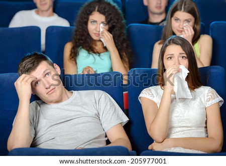 Exciting movie. Young people eating popcorn and drinking soda while watching movie at the cinema