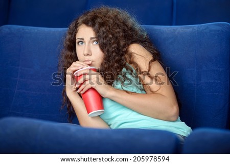 Women at the cinema. Beautiful young women drinking soda while watching movie at the cinema