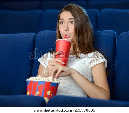 Women at the cinema. Beautiful young women eating popcorn while watching movie at the cinema