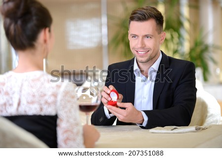 Elegant young man, a declaration of love for his girlfriend, gives the ring sitting in a restaurant