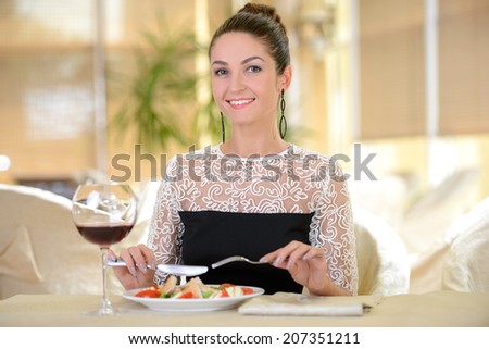 Elegant lady in colorful dress drinking wine, sitting in a restaurant