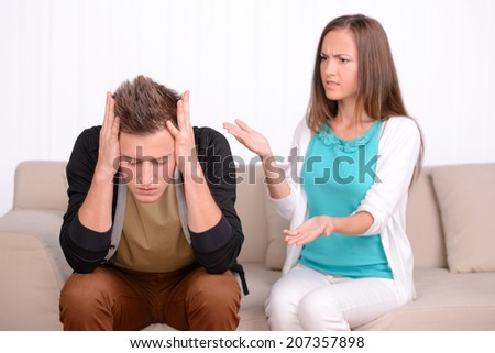 Young emotional couple sitting on sofa at home