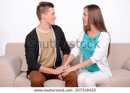 Young emotional couple sitting on sofa at home