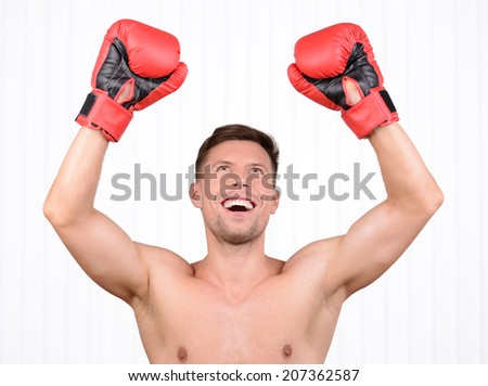 Always in great shape. Cheerful young muscular man boxer training in boxing gloves