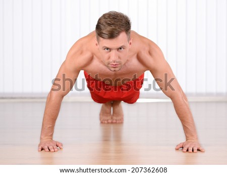 Push-ups. Young muscular man doing push-ups and looking at camera