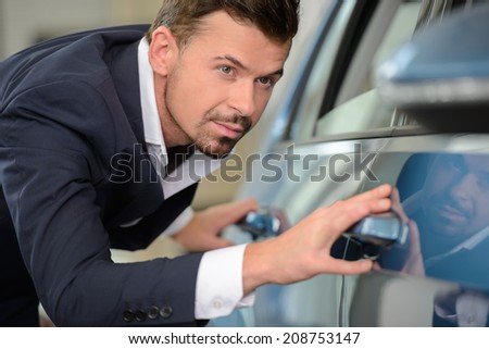 Every line should be perfect. Confident businessman examining a car at the dealership