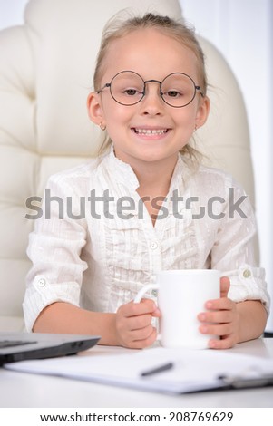 Little business lady. Cute little girl in glasses and formalwear sitting at the table and using laptop