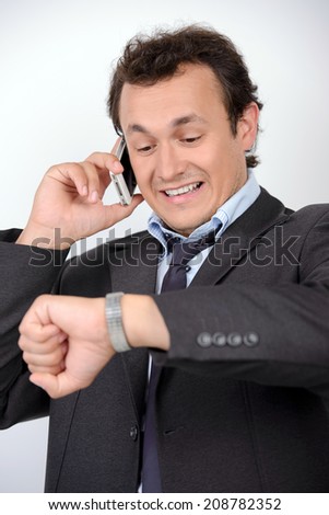 Portrait of worried young man in formalwear checking the time while standing against grey background