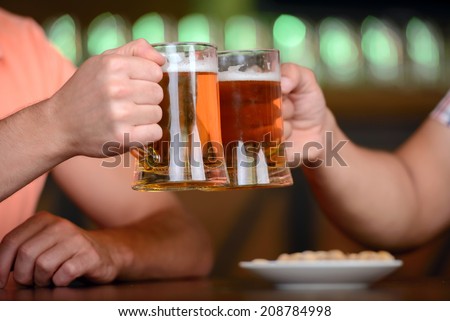 Close-up of young gay men to hold glasses of beer in a beer pub