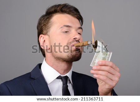 Rich businessman lighting cigar with $100 dollar bill
