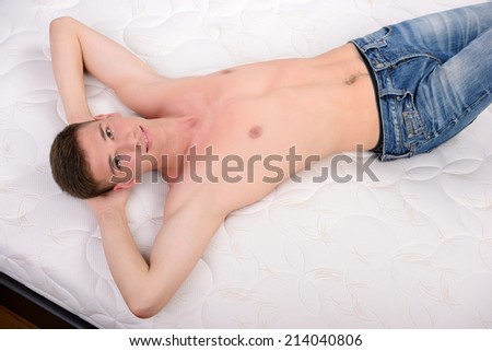 Enjoying his mattress. Young man lying on the bed. Quality mattress.