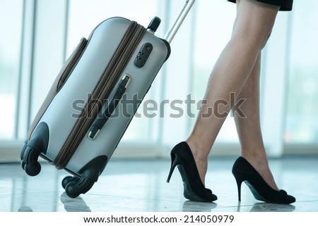 Business woman traveling with trolley. Women\'s legs, close-up