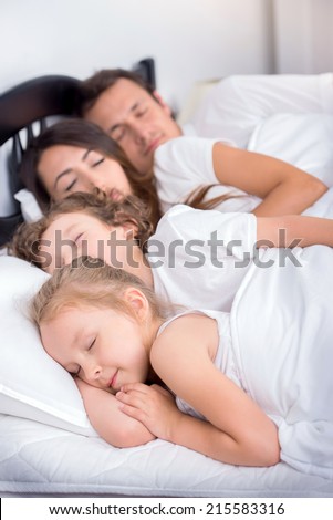 Family in the bedroom. Young family. Dad, mom, little boy and little girl sleeping in bed in bedroom at home