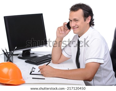 Portrait of an engineer using a PC and talking on the phone in the site office